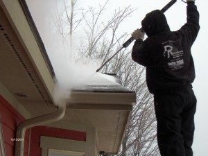 Rainbow Seamless employee using the ice removal machine on a snow and ice covered roof