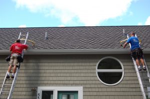 Two Rainbow Seamless employees working on the gutters of a home